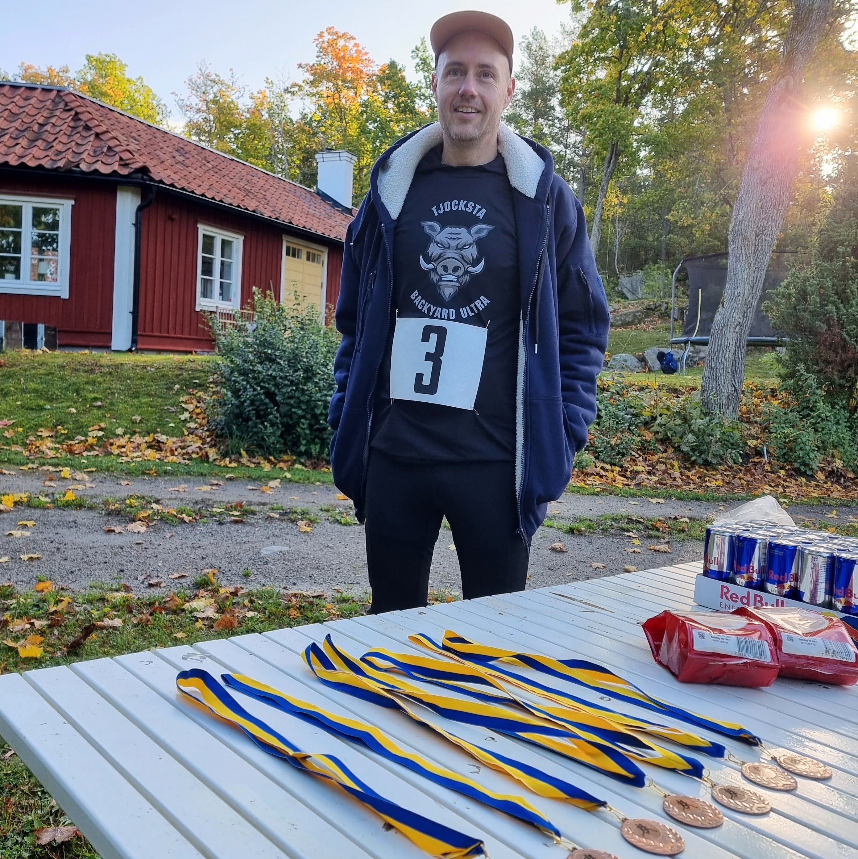 Löpare med nummerlapp framför ett rött hus i höstljus